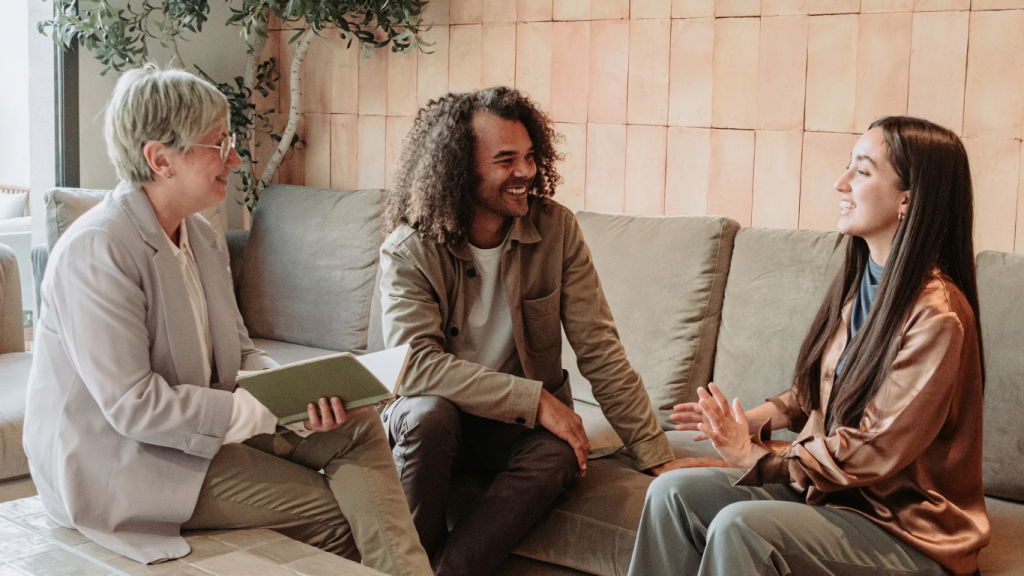 Three people sitting together, offering emotional support through eye contact and gentle body language, demonstrating co-regulation in a safe and supportive relationship.